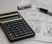 a calculator and a pen with financial papers on a desk