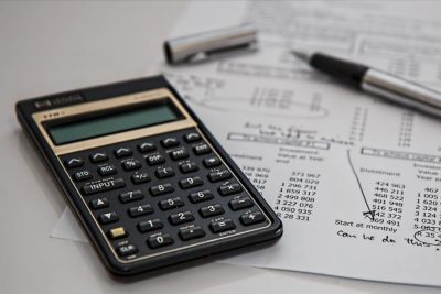 a calculator and a pen with financial papers on a desk