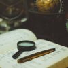 a magnifier and a pen laid on a dictionary representing a translation technique