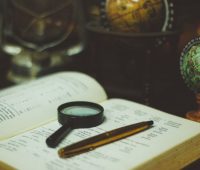 a magnifier and a pen laid on a dictionary representing a translation technique