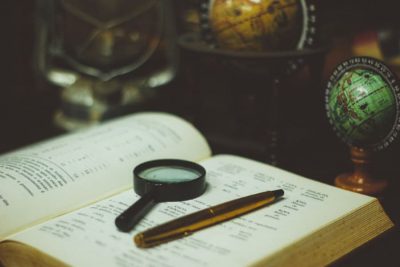 a magnifier and a pen laid on a dictionary representing a translation technique