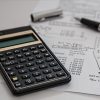 a calculator and a pen with financial papers on a desk